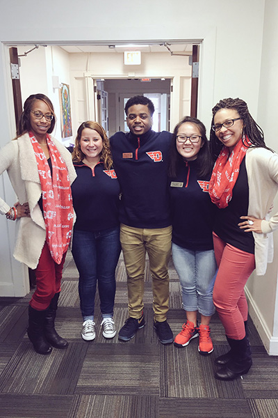 STudents and staff pose in a hallway in Alumni Hall