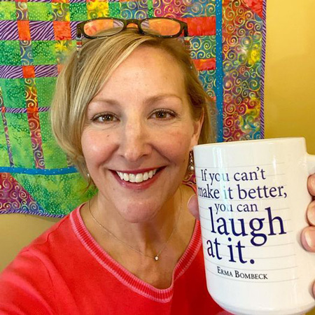 Katrina Kittle holding a mug with the quote," If you can't make it better, you can laugh at it."