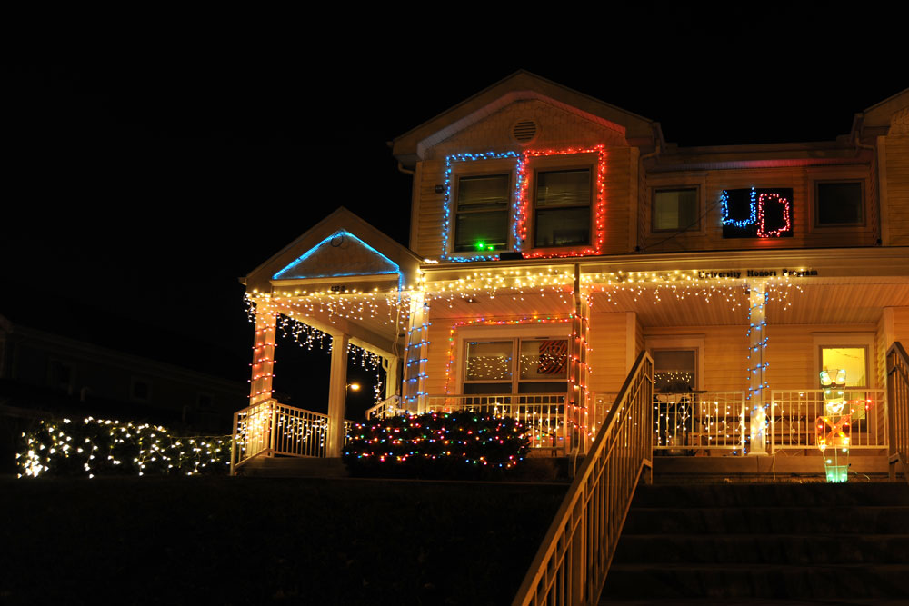 House with colored Christmas lights on the roof line and bushes