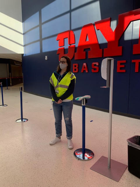 A student stands in front of a Dayton Basketball sign in UD Arena.
