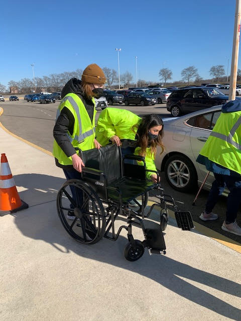 Two students prepare a wheelchair to help transport a patient