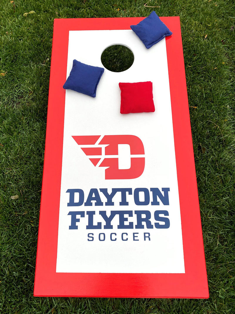 Cornhole board says "Dayton Flyers Soccer."