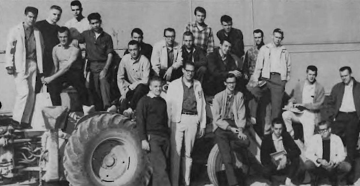 Students stand on or near a tractor while posing for a class photo