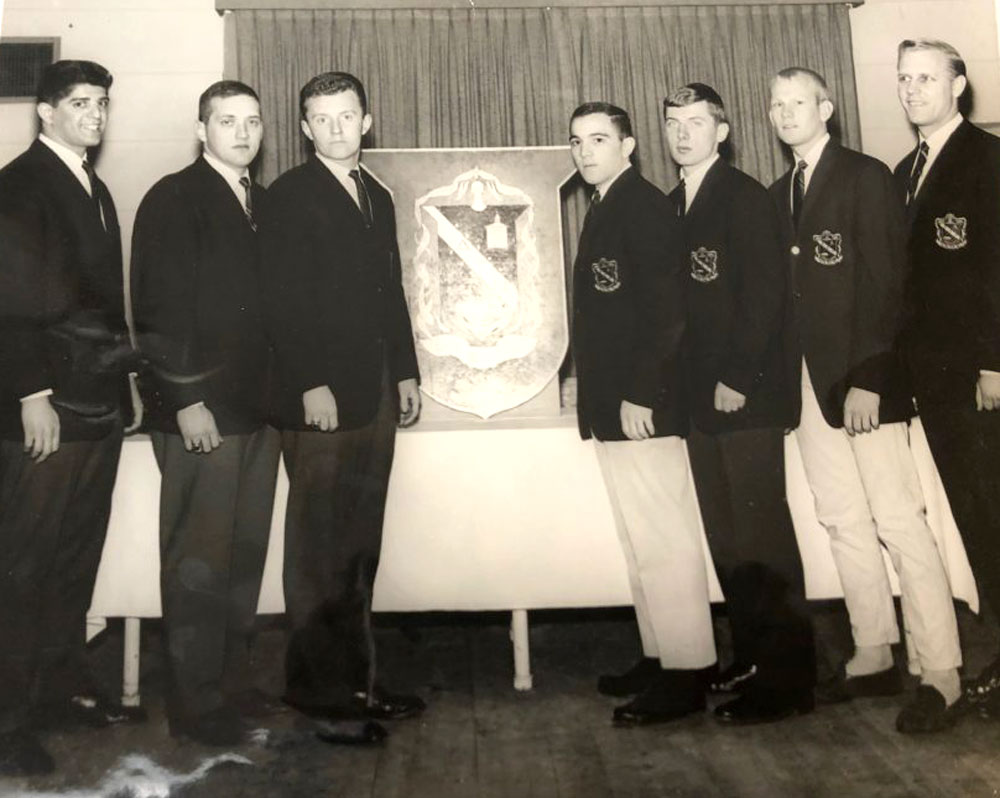 Seven men stand in DTN jackets