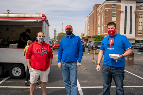 Giving day volunteers dressed in red and blue in front of food trucks
