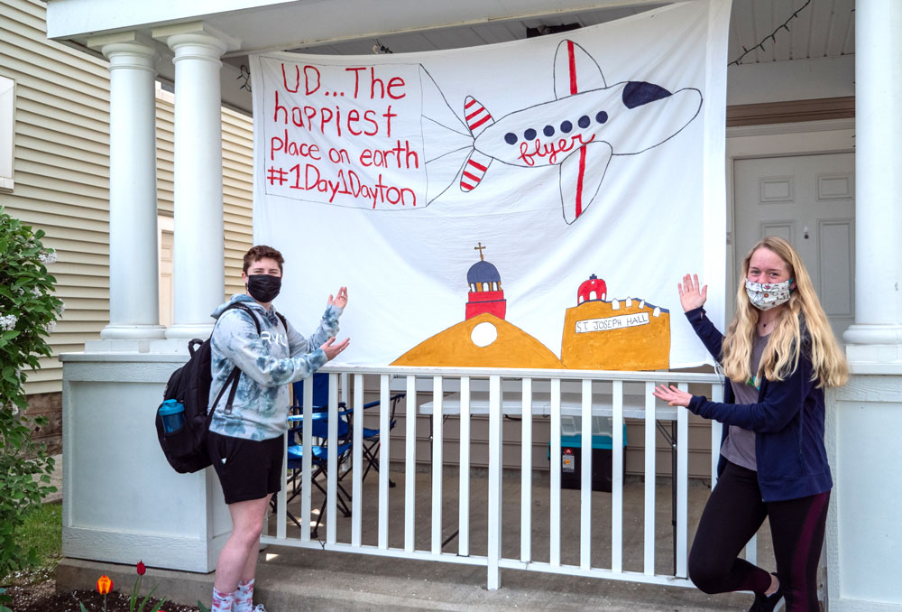 Two students show their sheet sign "UD ... the happiest place on earth."