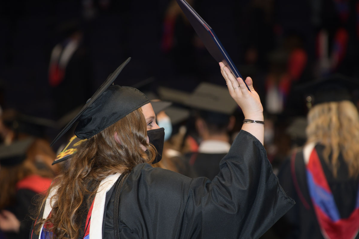 Student holding a diploma waves at her family
