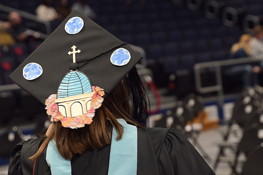 student with a mortar board decorated as the UD chapel
