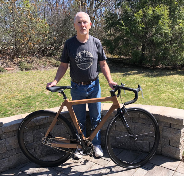 Tom Wing stands with his wooden bike