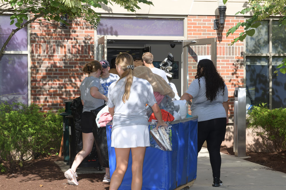 Students push a cart full of belongings into a residence hall