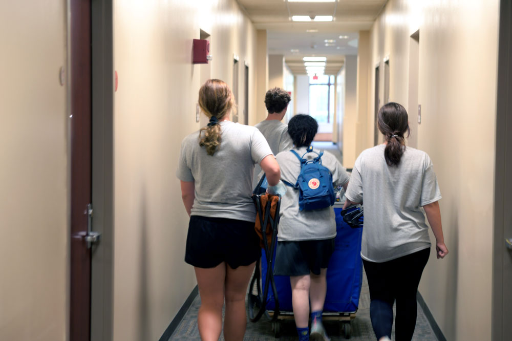 Students push a cart down the hallway