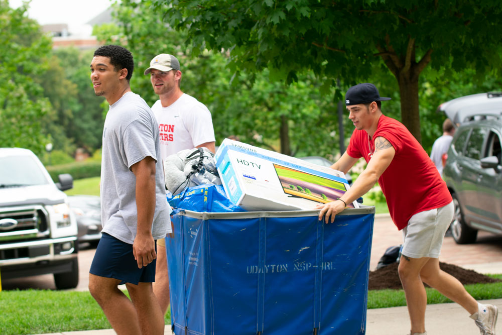 Three students push a cart