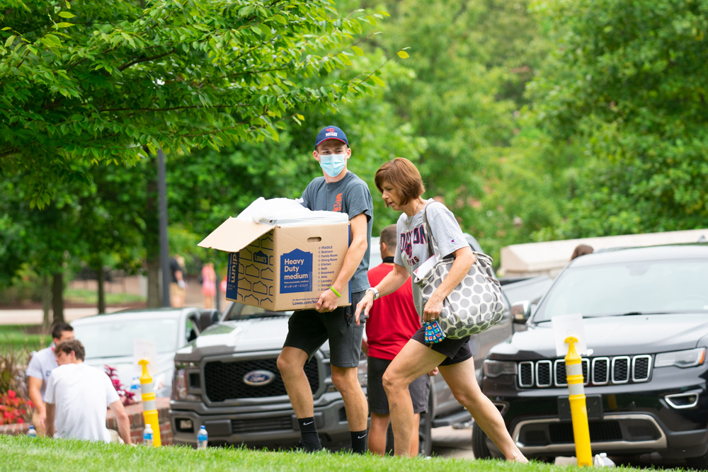 Mom and son walk belongings up to a residence hall. 
