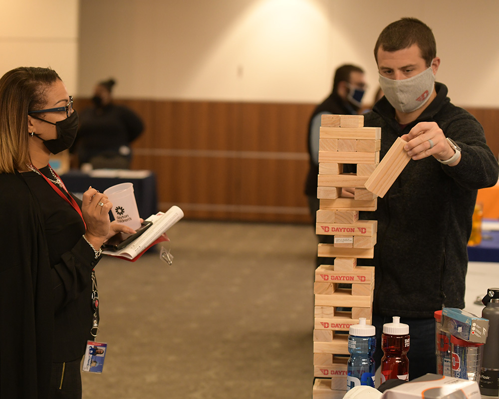 Two people play with wooden block tower game