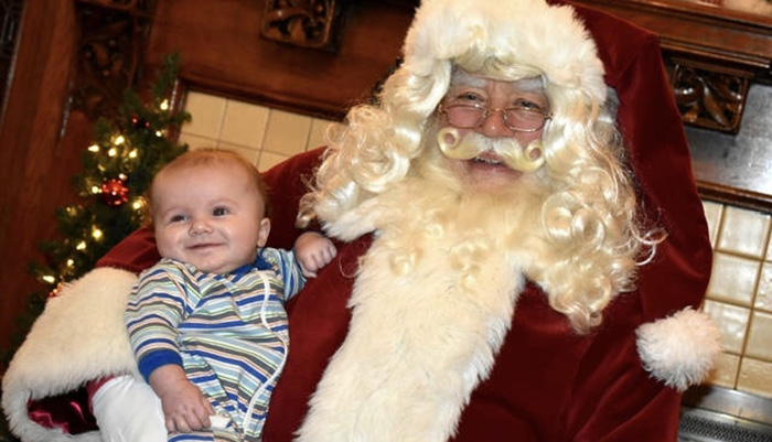 Chuck Karehm dressed as Santa holding a small baby.