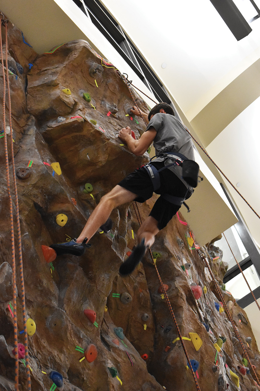 Student climbing up the climbing wall.