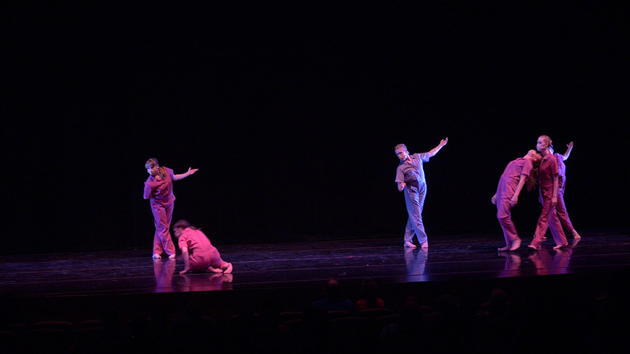 Several dancers performing a piece on stage.