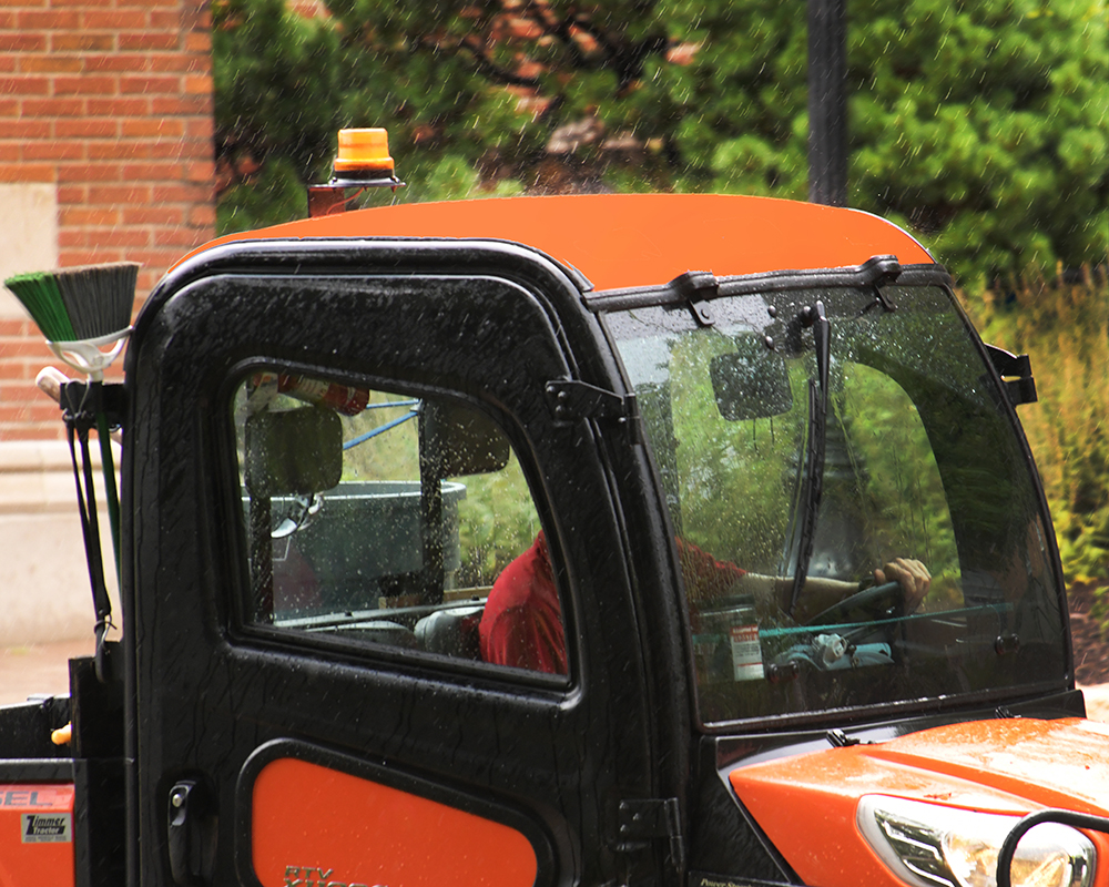An orange maintenance vehicle drives in the rain