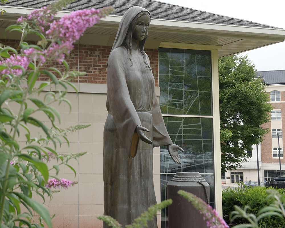 Mary of Cana statue near a butterfly bush