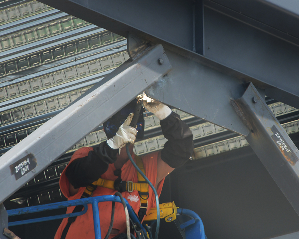 A welder works on metal beams for a new building