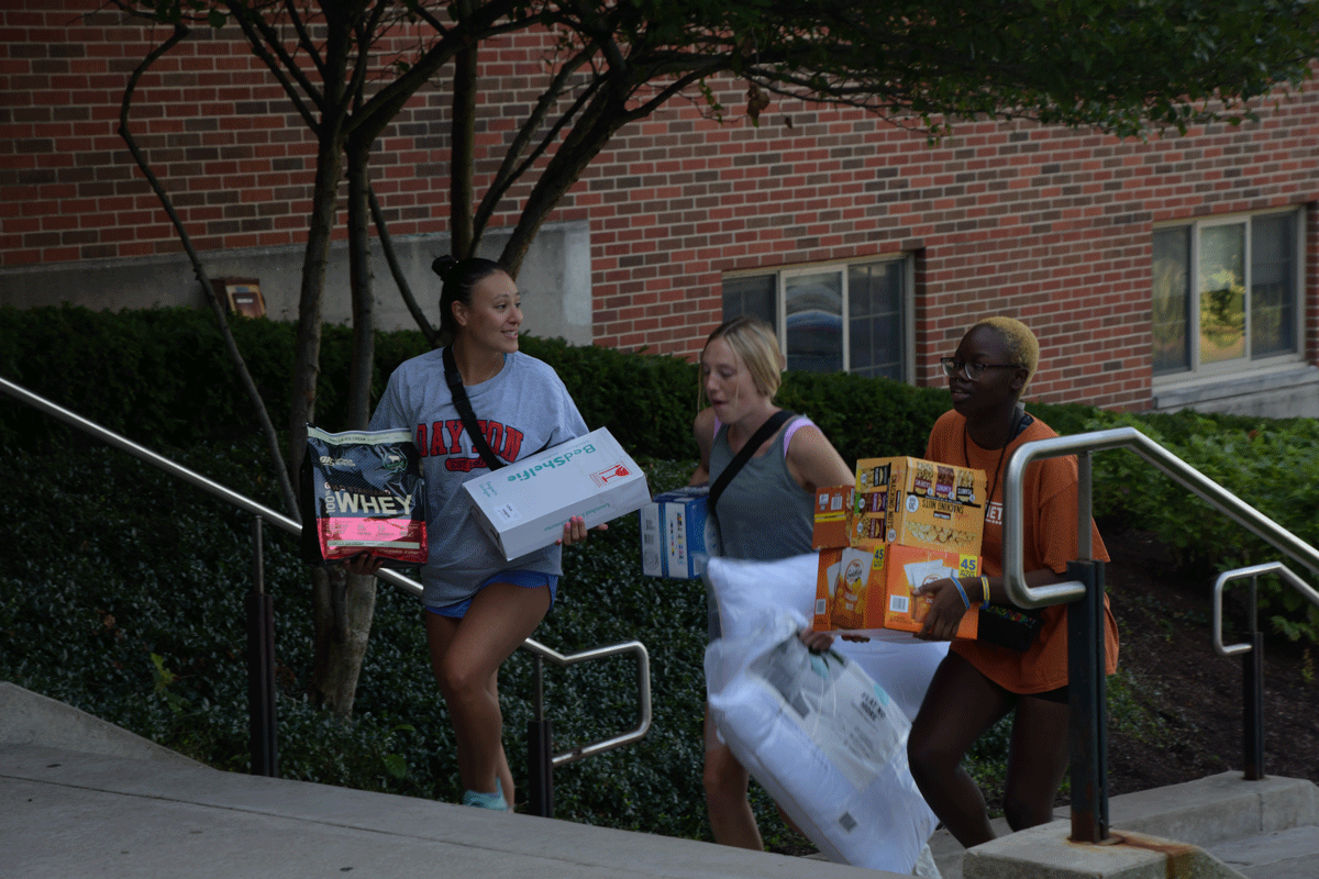 A group of young ladies bring boxes of snacks up the steps  of Marycrest.