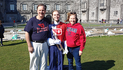 Rebecca stands with her parents in front of a castle in Ireland.