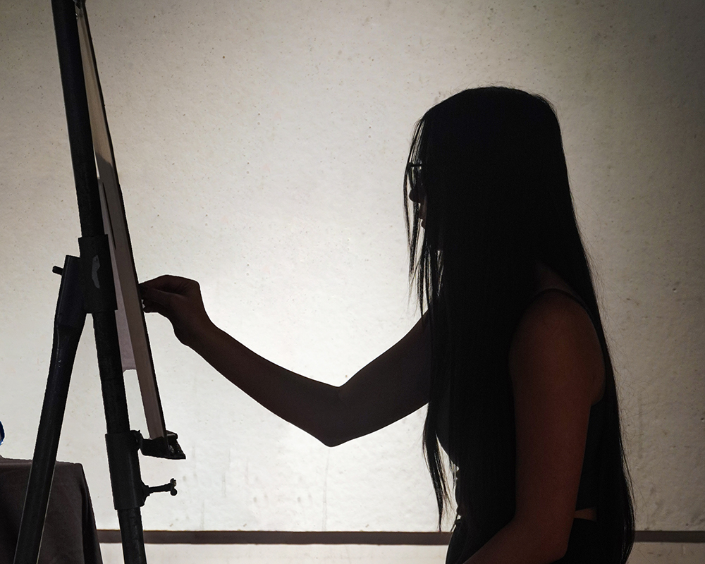 Student at an easel in silhouette
