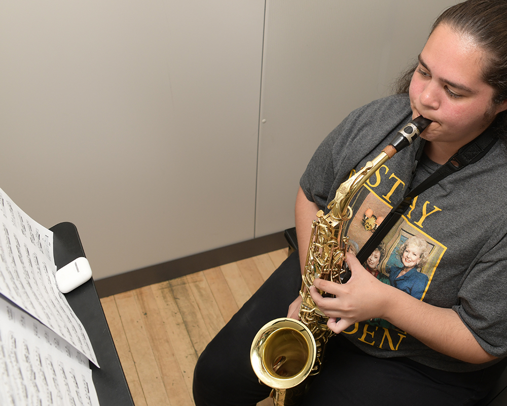 A music student practices playing saxophone
