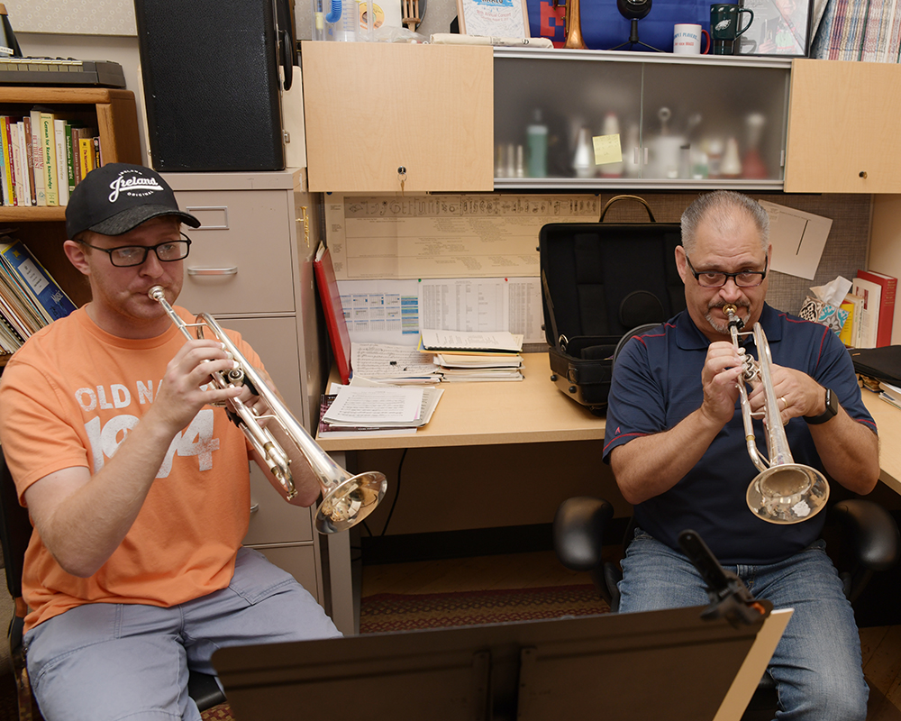 A student and an instructor play the trumpet