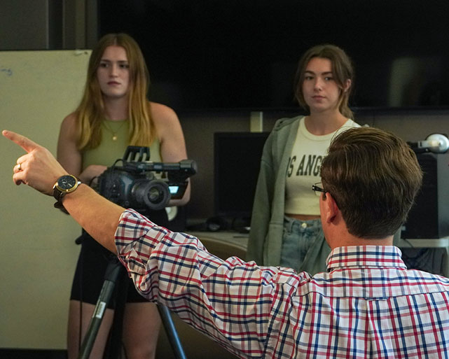 Professor assists students with film process.