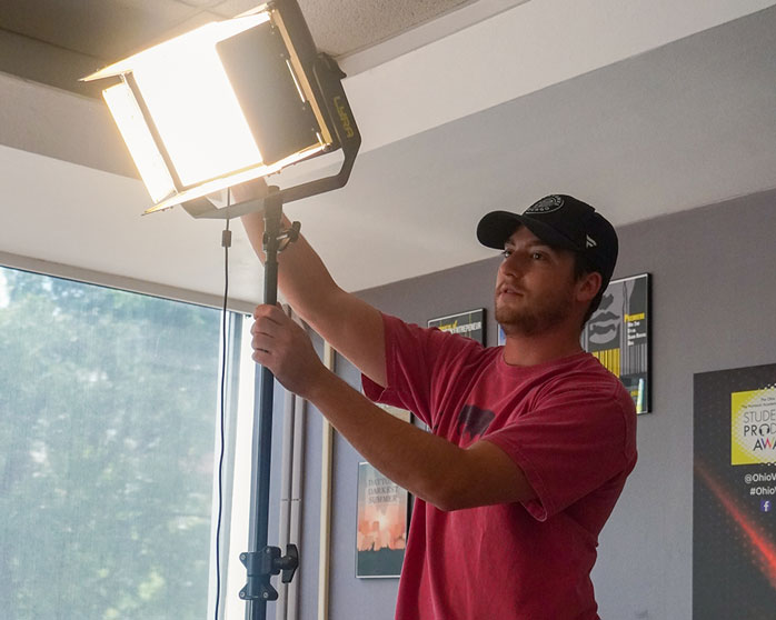 A student checks the lighting behind the camera.