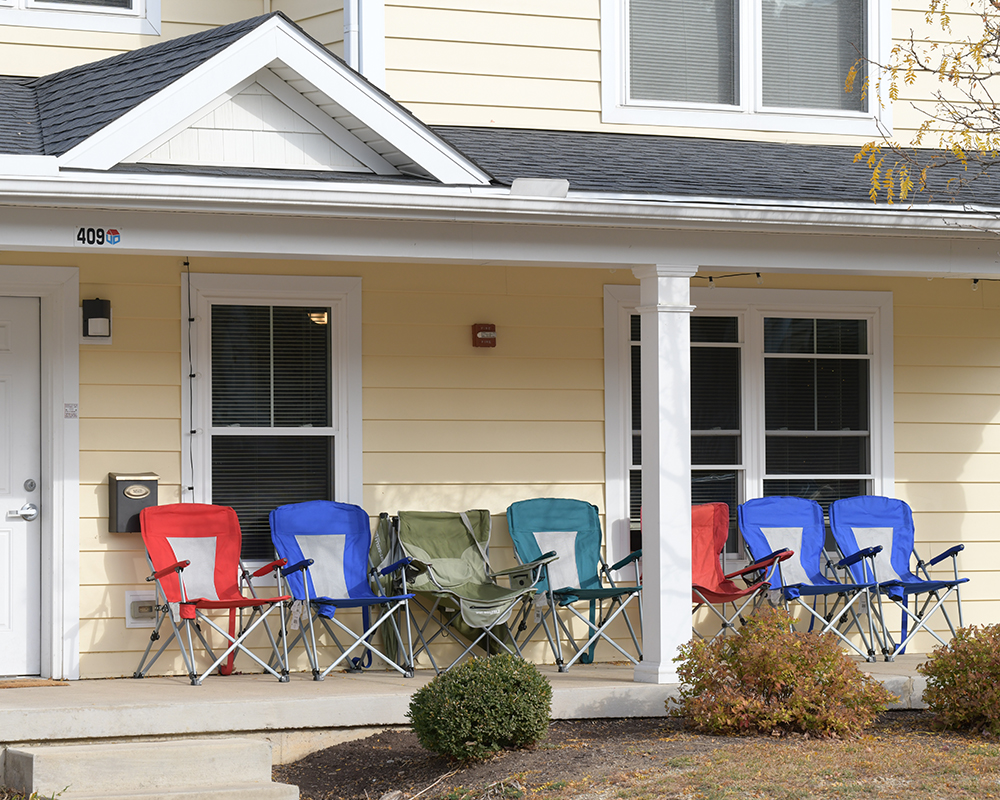 Several chairs lined up on a front porch