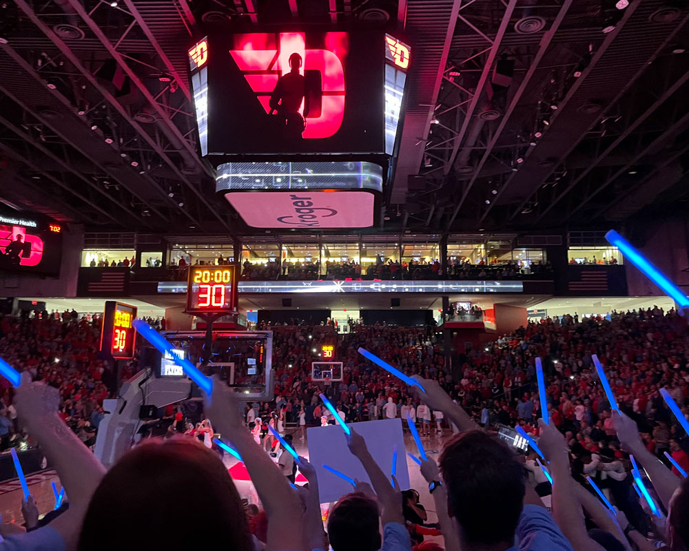 Flyers wave blue glow sticks in the student section before a Dayton basketball game.