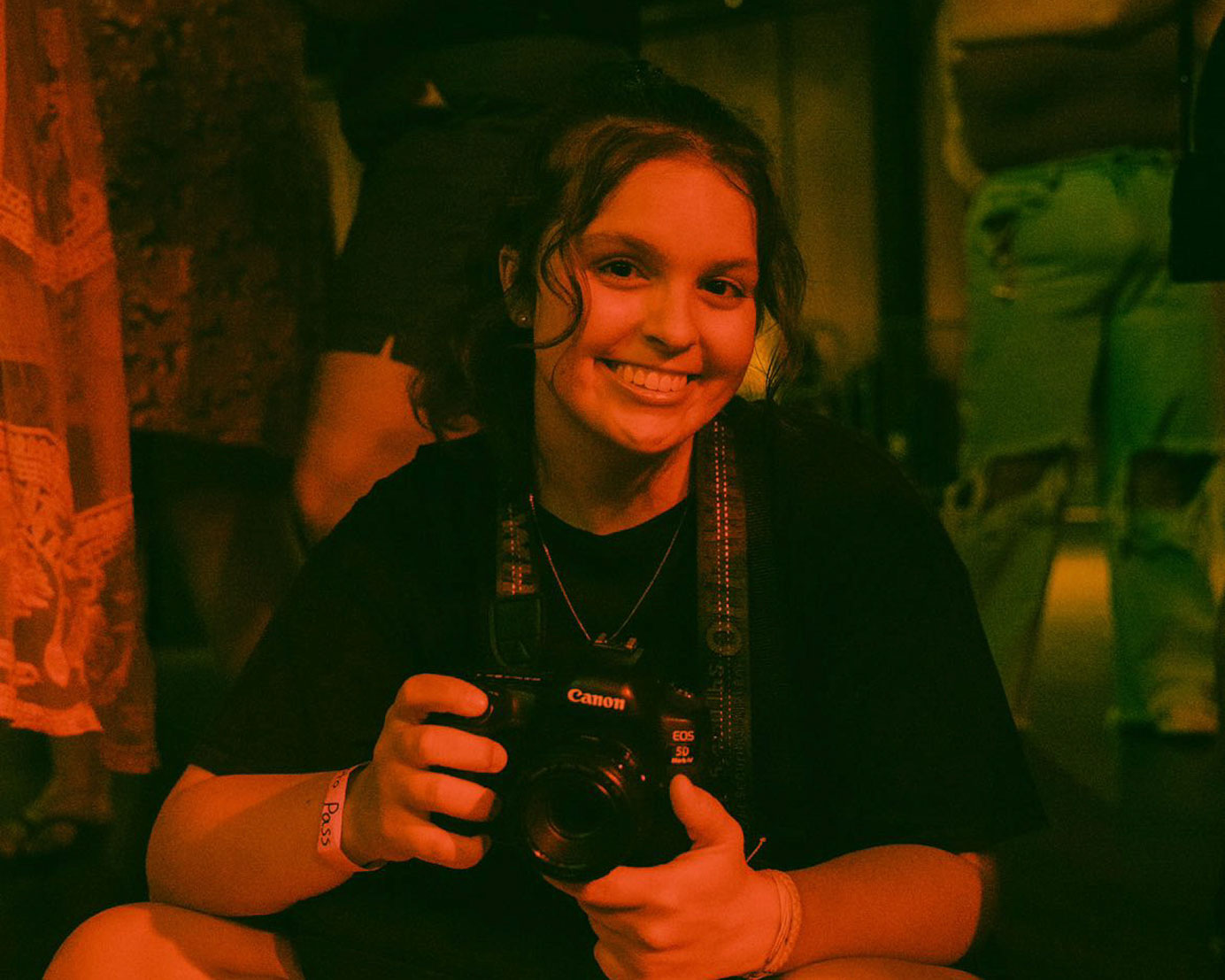 The photojournalist, Kennedy Kish, holds a camera before a concert.