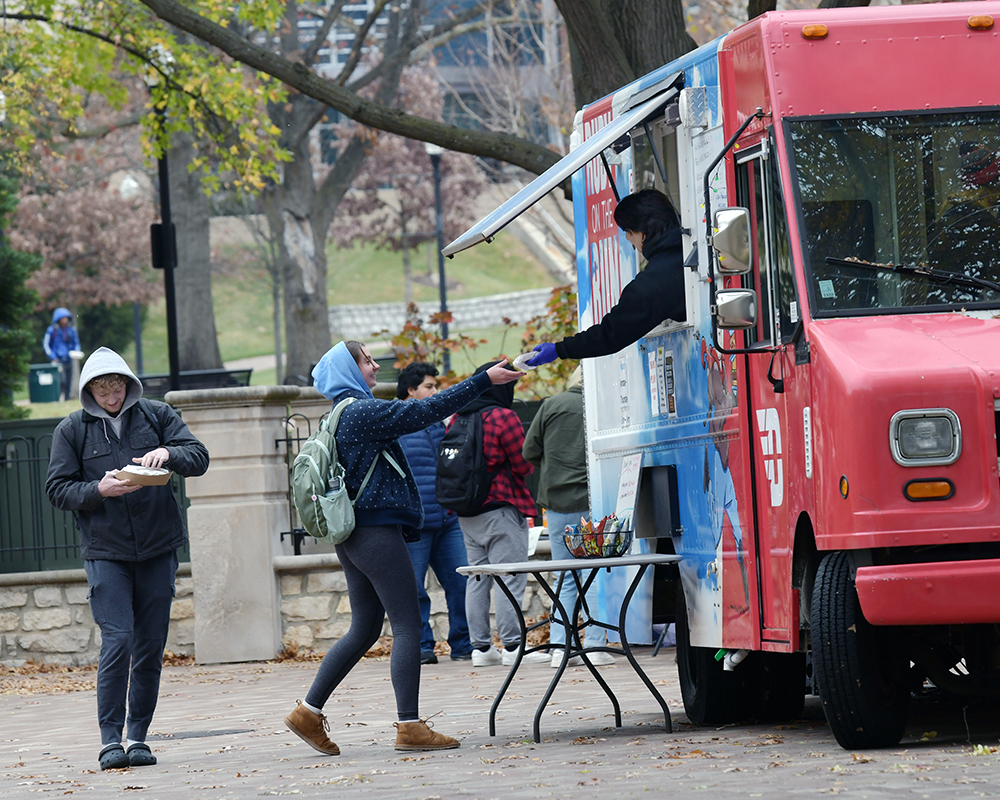A student picking up food from the Rudy on the Run food truck