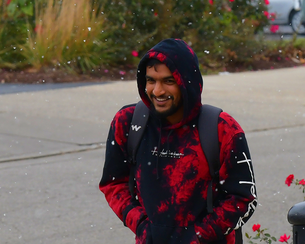 A student smiles while walking through snow flurries