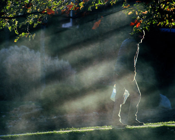 A grounds worker walks through the mist of lawn sprinklers