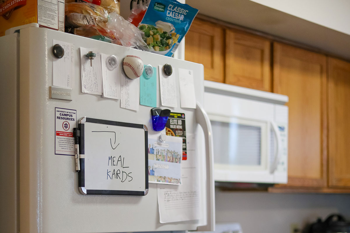 A fridge with magnets and index cards and a whiteboard that reads "Meal Kards."