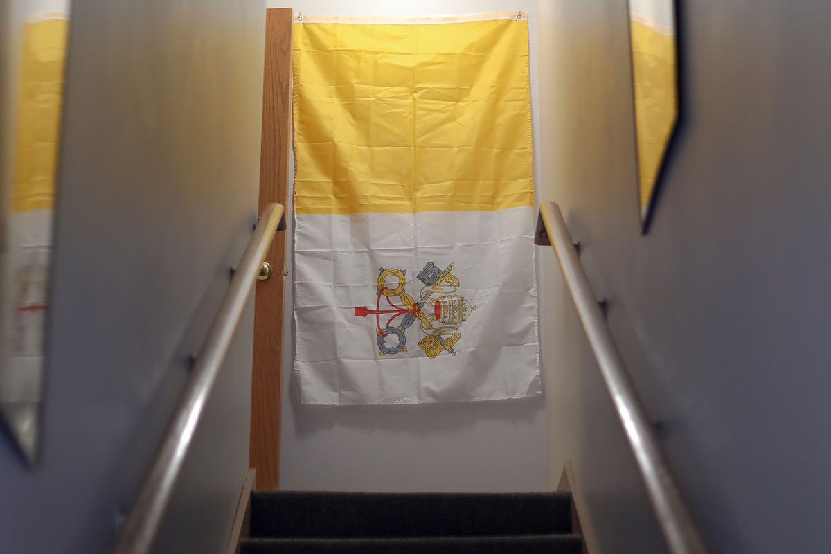 A flag of Vatican City at the stop of a staircase.