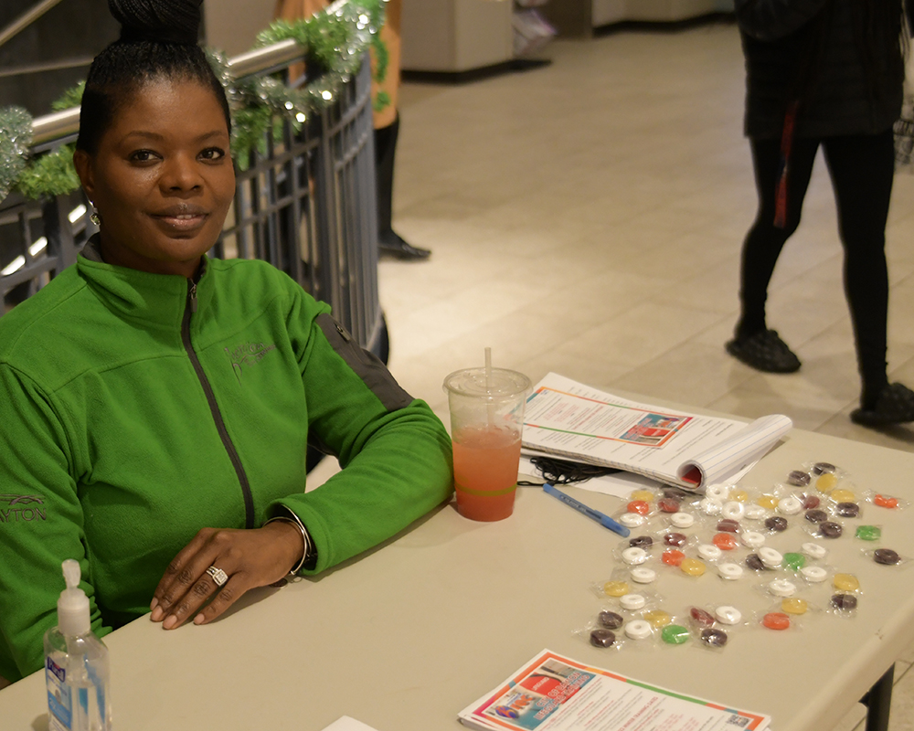 A woman in green sits at a table in the Kennedy Union lobby
