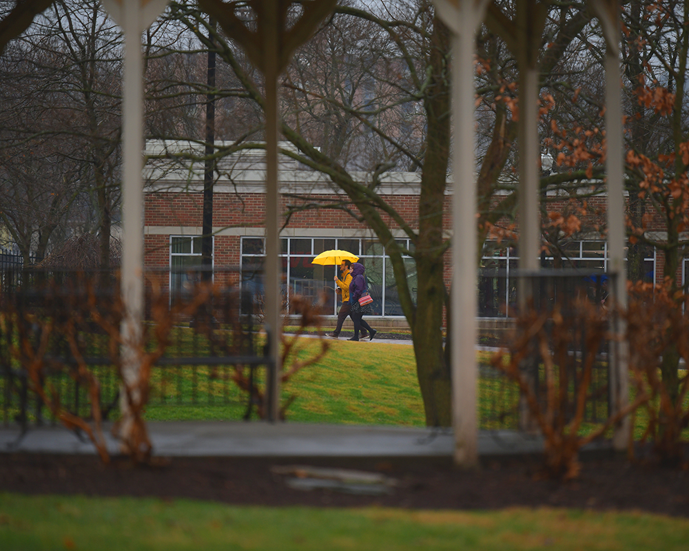 Students share an umbrella in the rain
