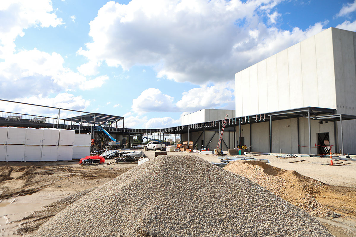 A wide shot of part of the construction site with piles of gravel, beams, and other construction equipment.