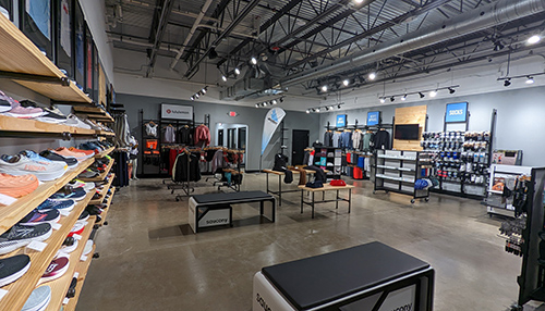 The interior of the new Runners Plus store, clothes on racks and wall of shoes.