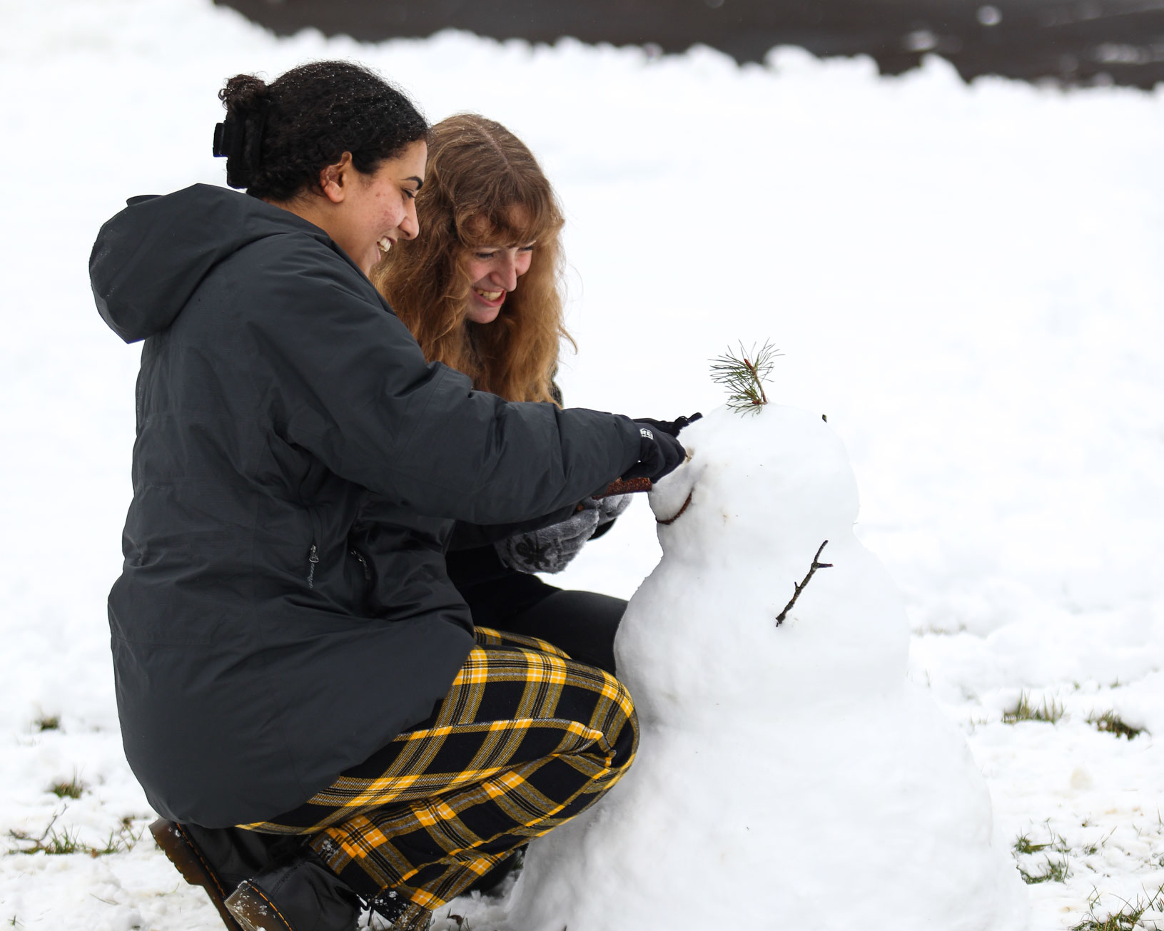 Two students add eyes to their snowman