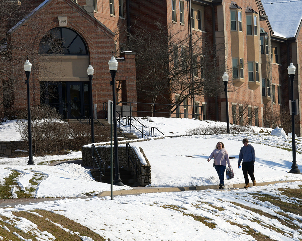 Students walk a snowy sidewalk