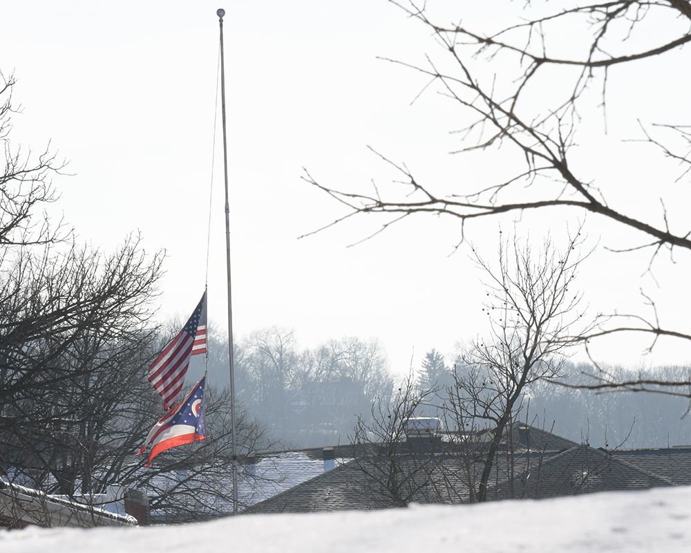 Flags fly half staff on a snowy day