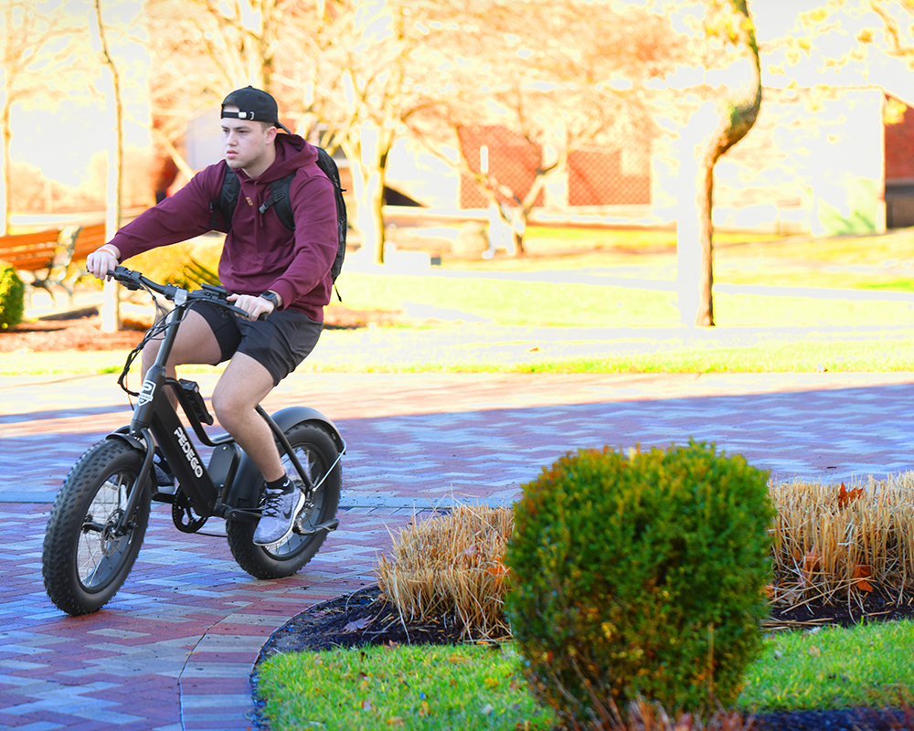 A student riding a bicycle in shorts