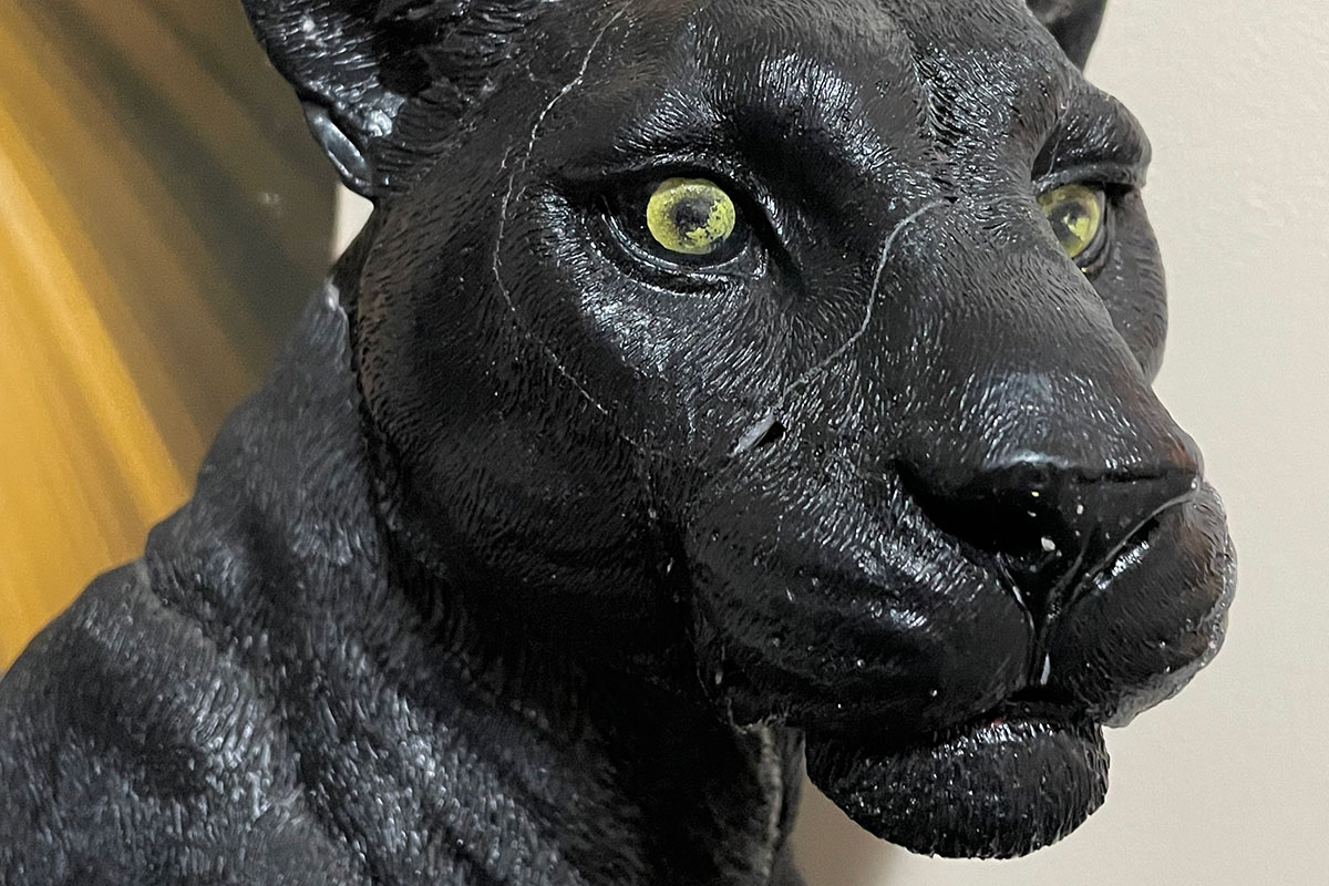 A closeup of a plastic black panther statue.