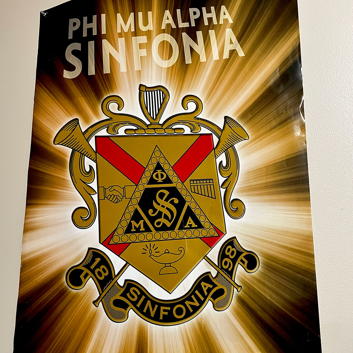 The fraternity's logo on a poster in gold and black colors.