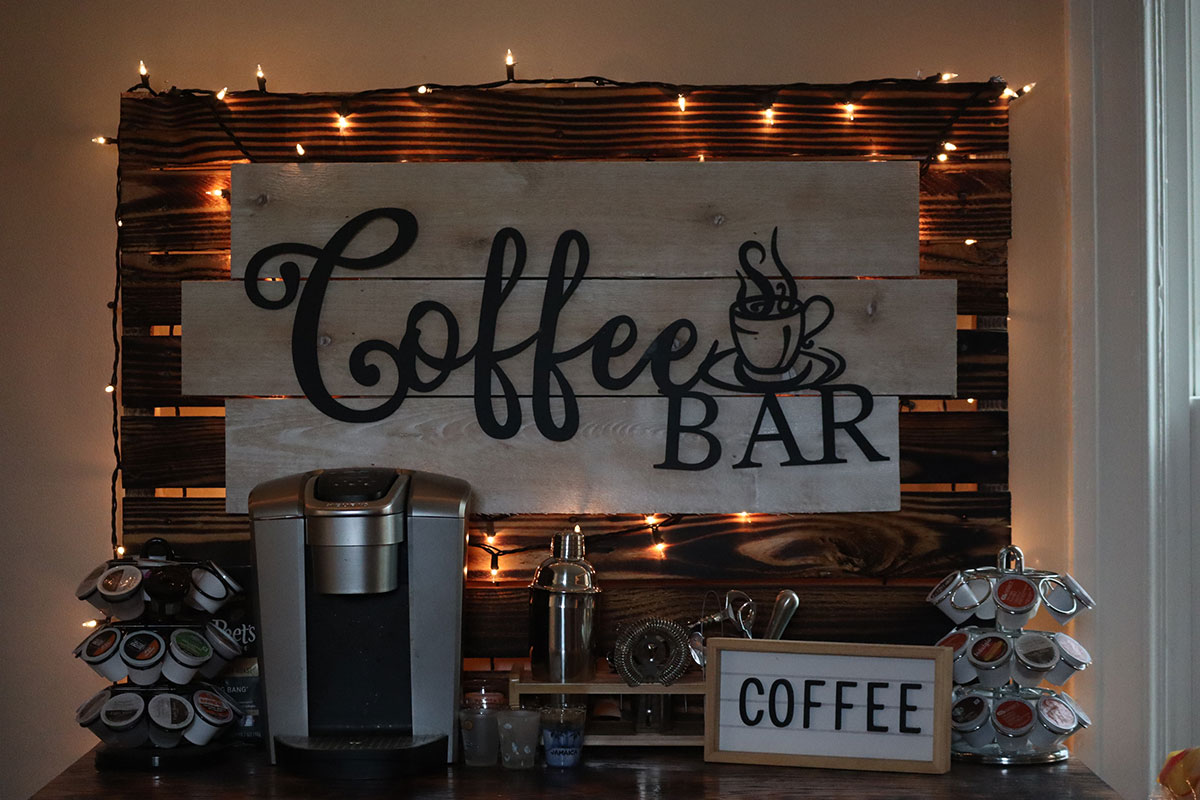 A table with a Keurig coffee maker and a large sign that reads "Coffee bar" in decorative font.
